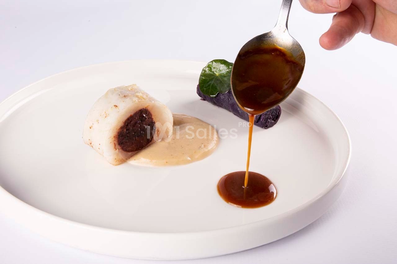 Un plat gastronomique avec un rouleau de poisson farci, purée violette et sauce versée à la cuillère.