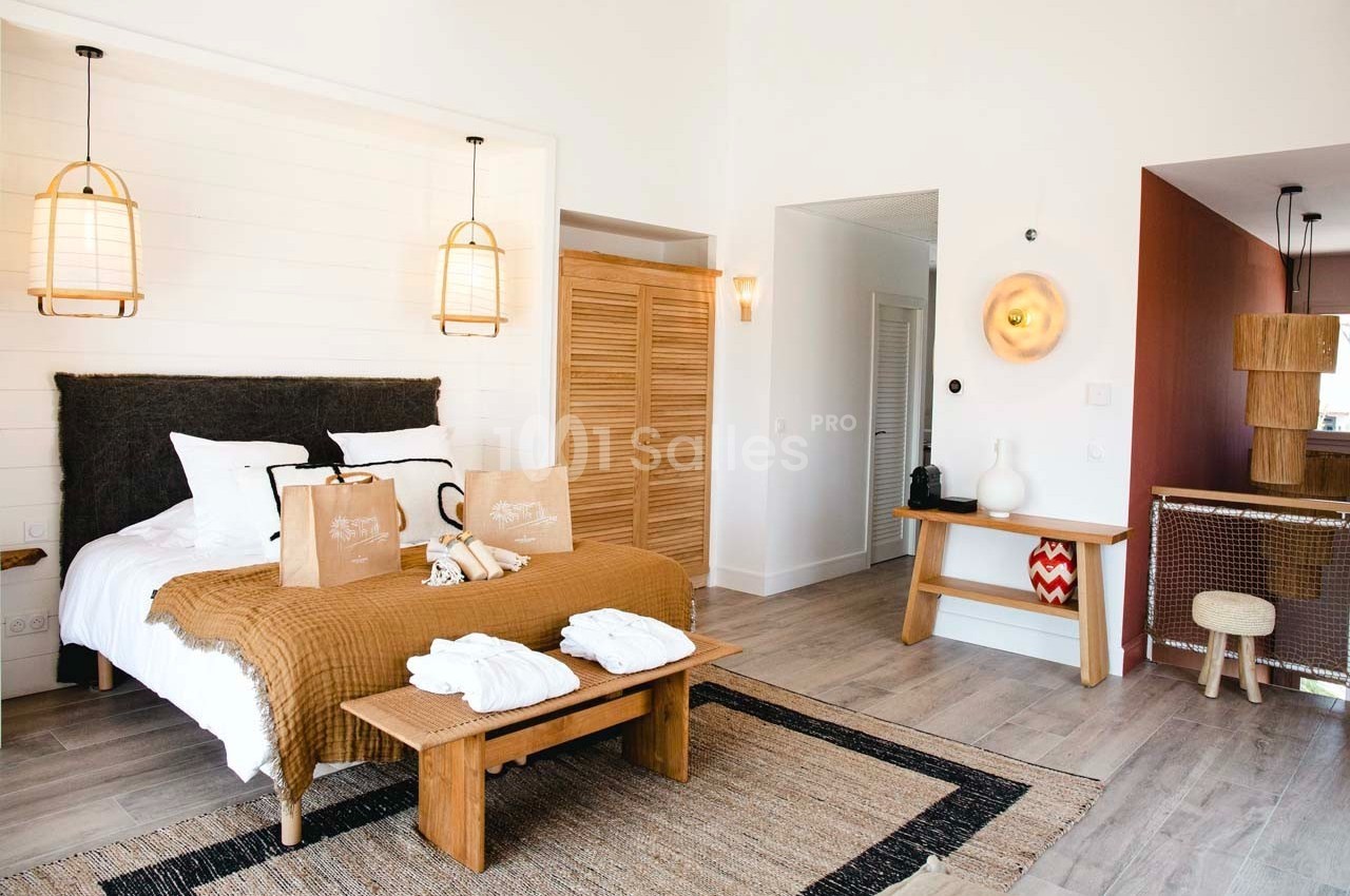Chambre lumineuse avec lit double, linge beige, mobilier en bois et décorations modernes dans un style épuré.