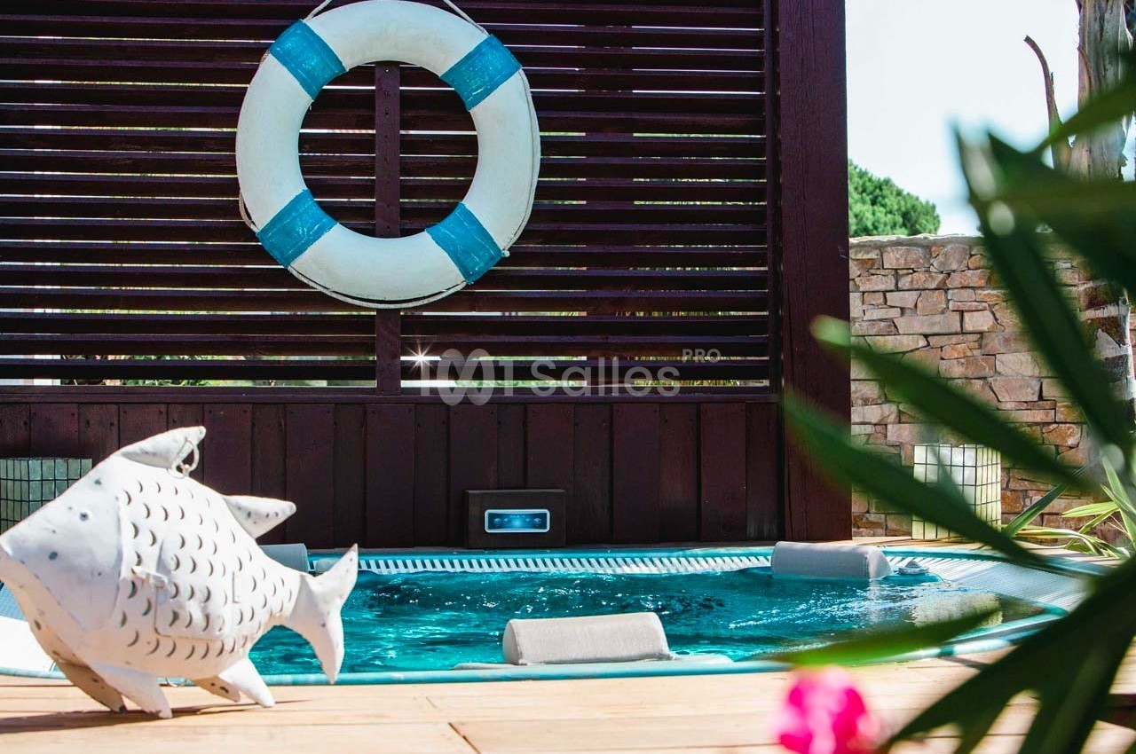 Piscine extérieure avec bouée accrochée à une cloison en bois, décoration en forme de poisson au premier plan.