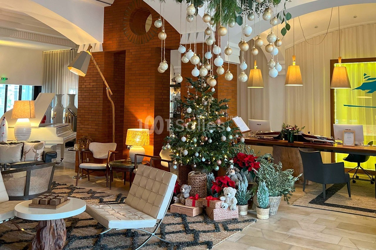 Décoration festive dans un salon élégant avec un sapin de Noël, des guirlandes suspendues et des meubles modernes.