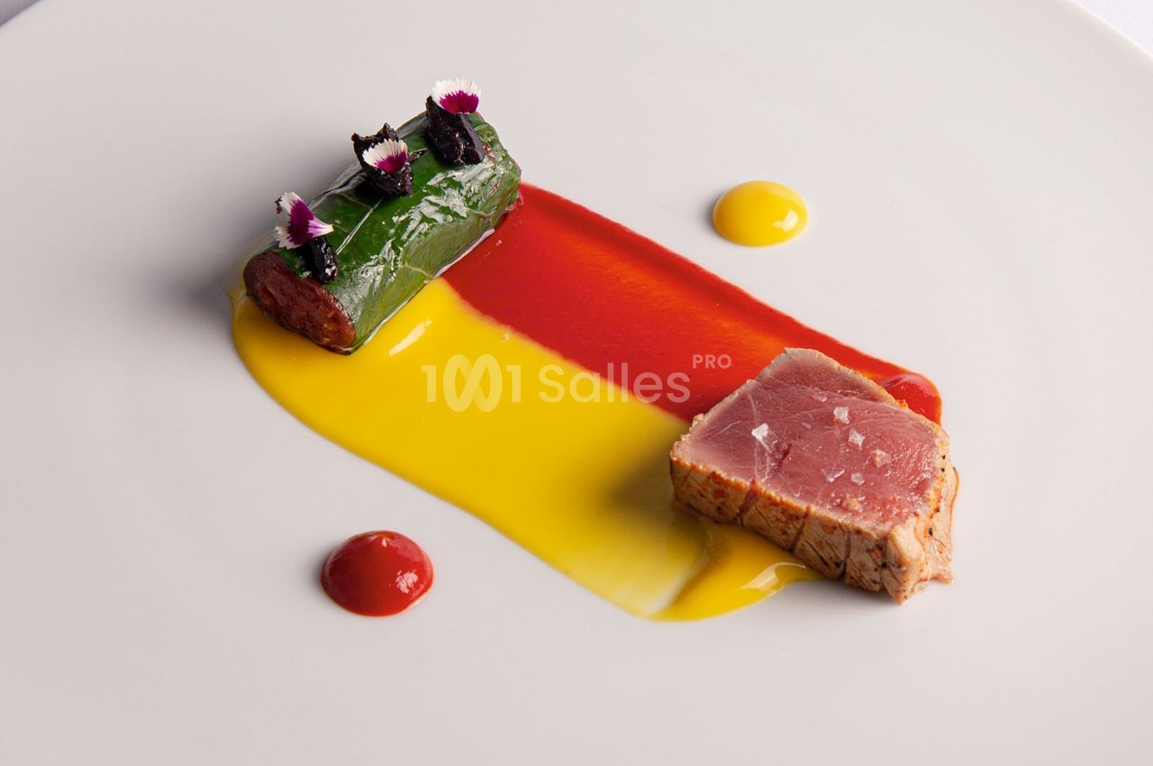 Assiette gastronomique avec filet de thon mi-cuit, rouleau garni, et sauces colorées rouge et jaune.