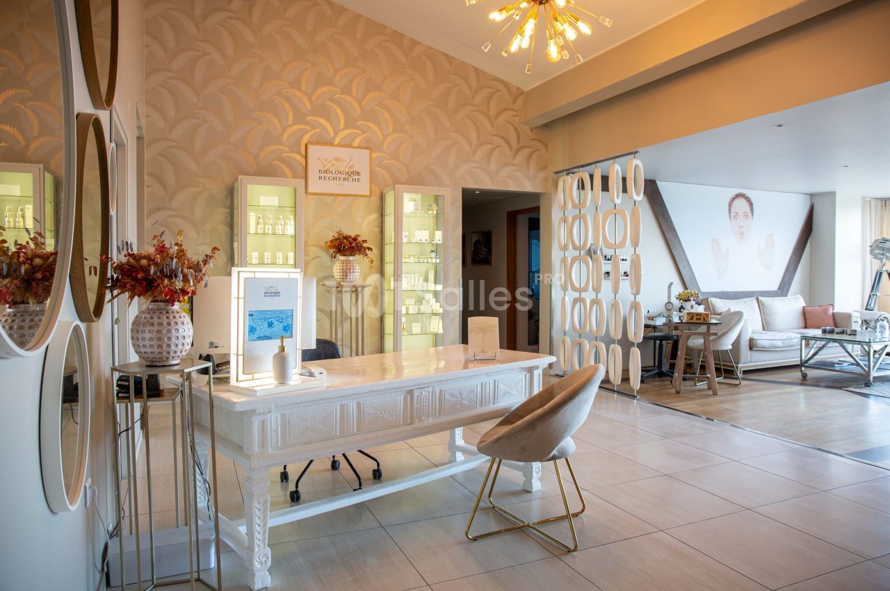 Intérieur d'un salon moderne avec un bureau blanc, des étagères éclairées, des décorations élégantes et un coin salon.