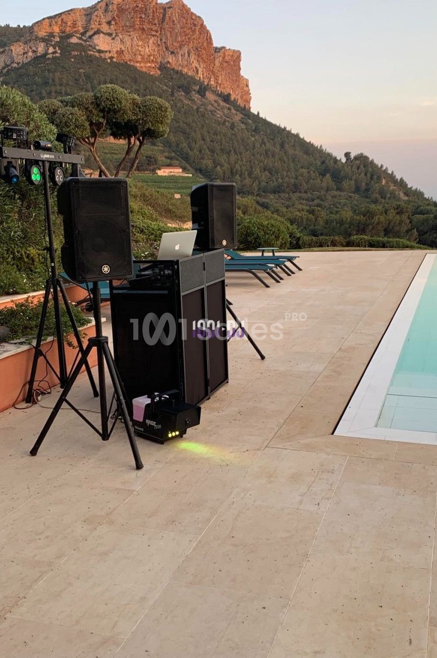 Équipement de sonorisation installé en extérieur près d'une piscine, avec vue sur des collines et un ciel dégagé.