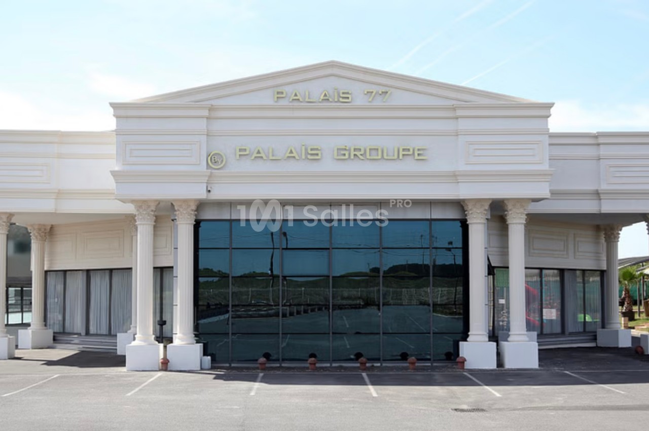 Façade d'un bâtiment blanc avec des colonnes et des inscriptions ’Palais 77’ et ’Palais Groupe’ sur le fronton.