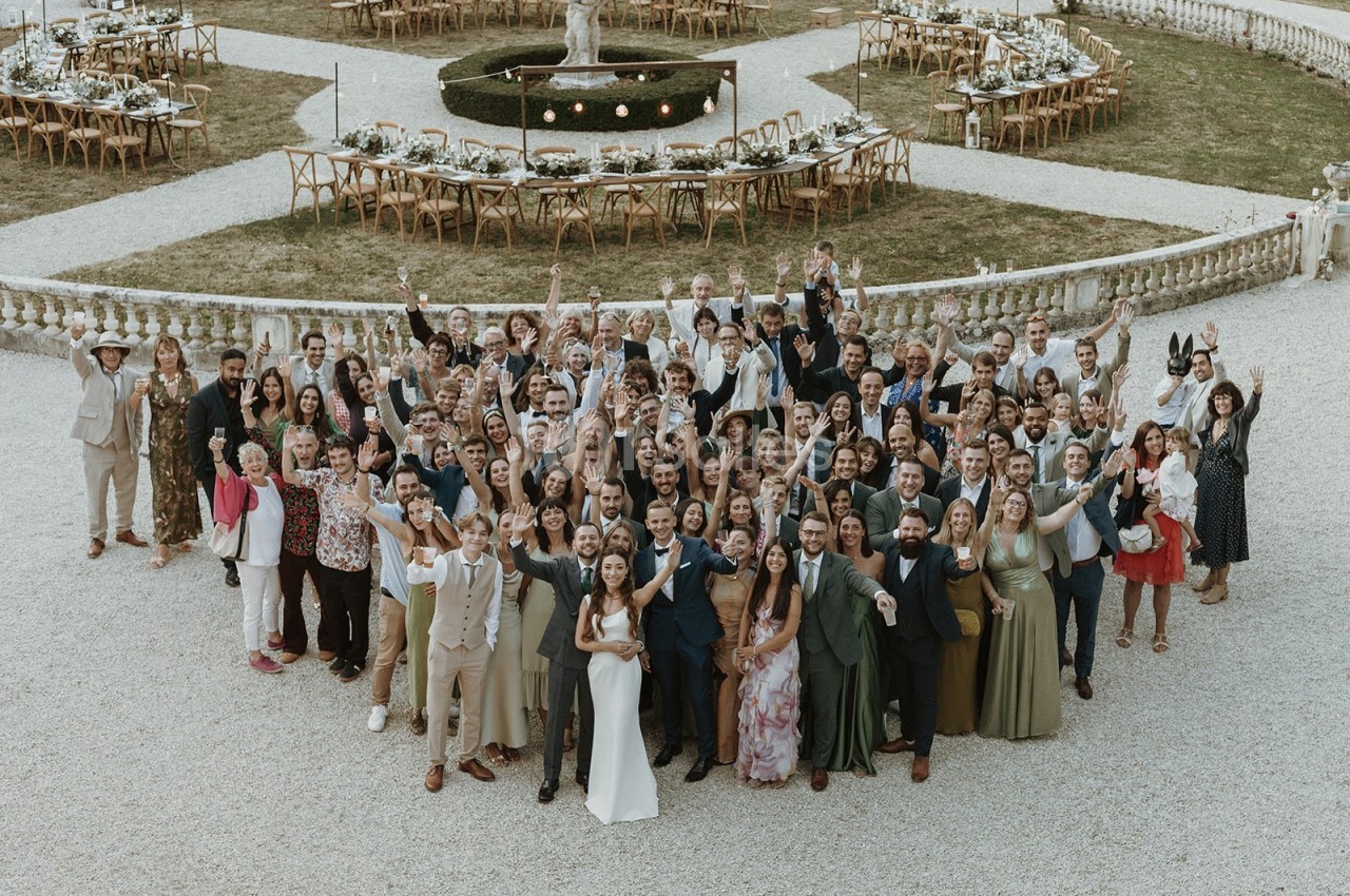 Groupe de personnes posant ensemble en plein air devant des tables décorées dans un cadre élégant.
