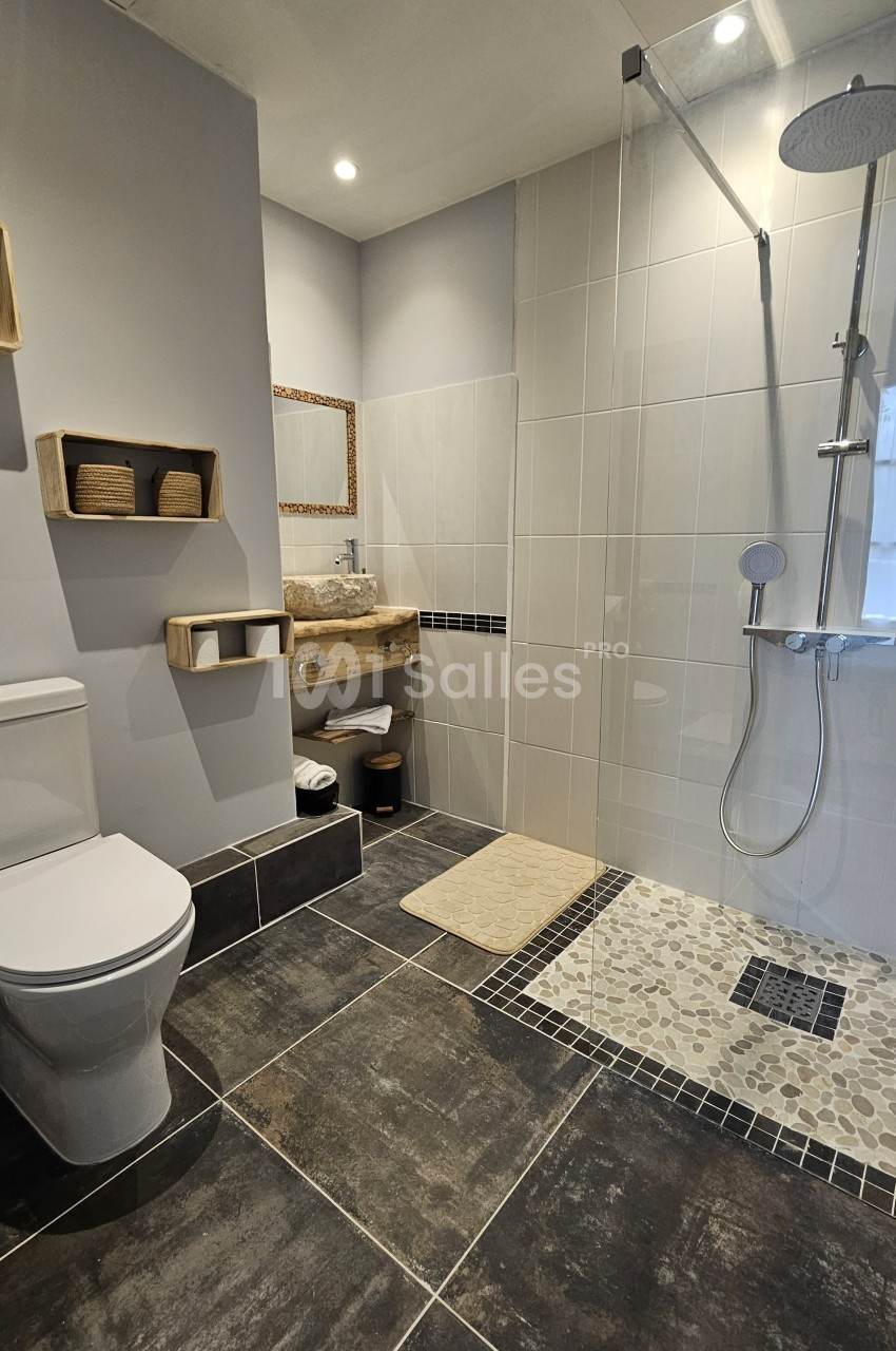 Salle de bain moderne avec douche à l'italienne, toilettes, lavabo en bois et étagères murales.