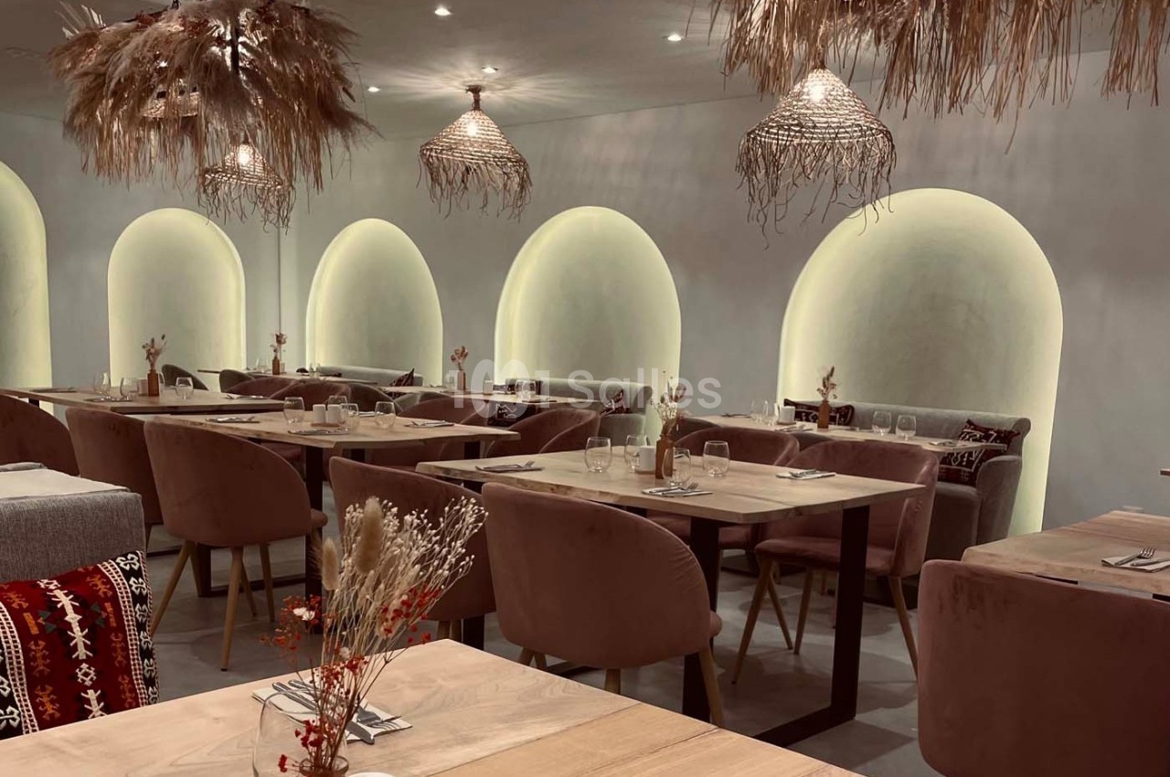 Salle de restaurant élégante avec des tables en bois, des chaises rembourrées et des luminaires en fibres naturelles.