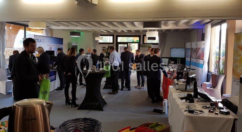 Des personnes échangent dans un espace d'exposition avec stands, matériel technologique et affiches informatives.