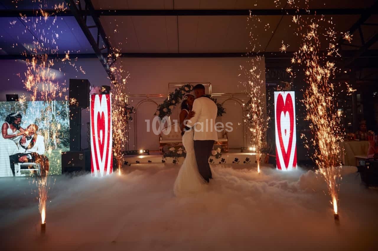 Un couple danse au milieu d'une piste entourée de fumée, d'étincelles et d'écrans affichant des cœurs rouges.