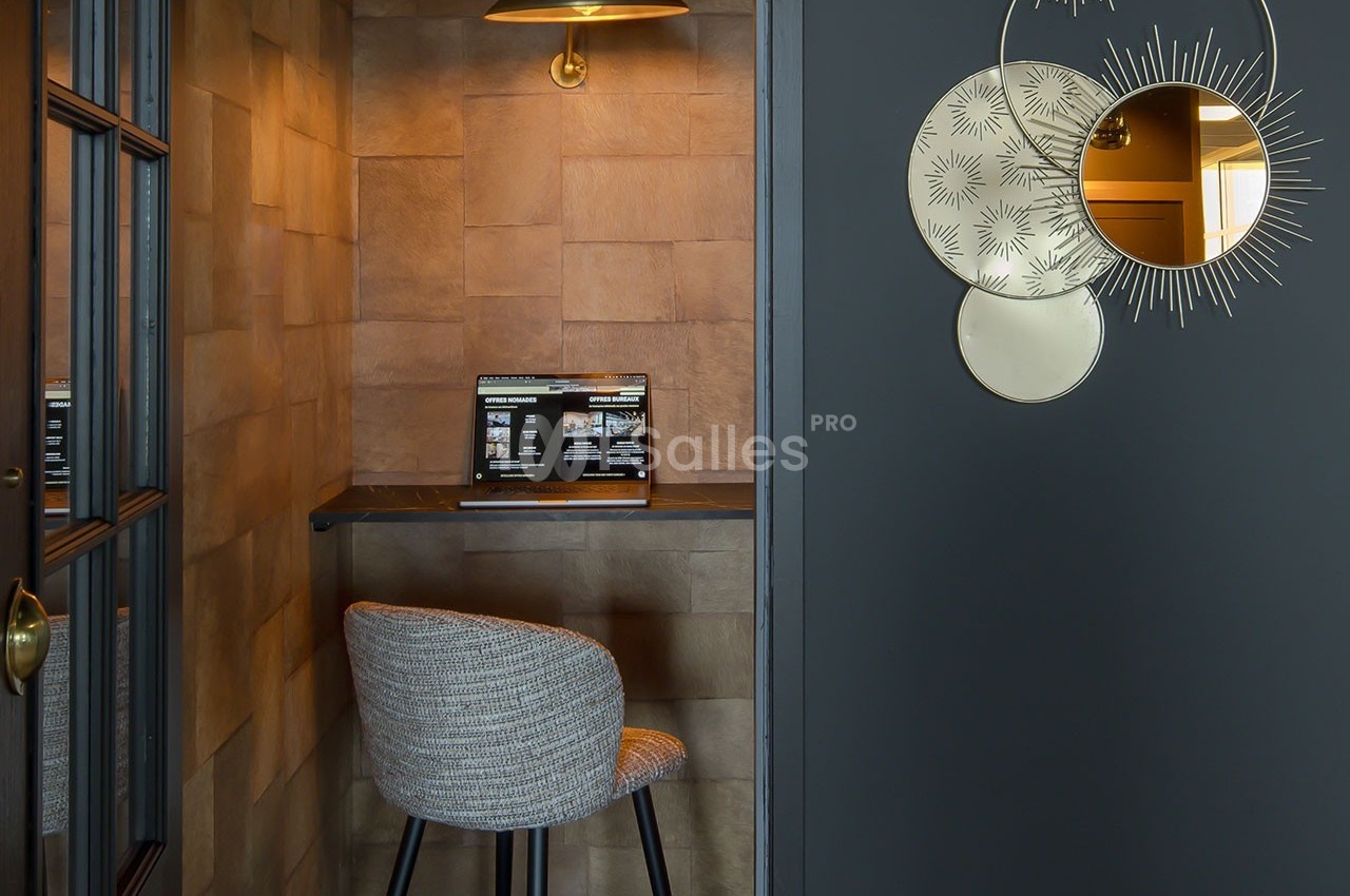 Coin bureau avec chaise rembourrée, tablette en bois, ordinateur portable et lampe suspendue, décoré de miroirs muraux.
