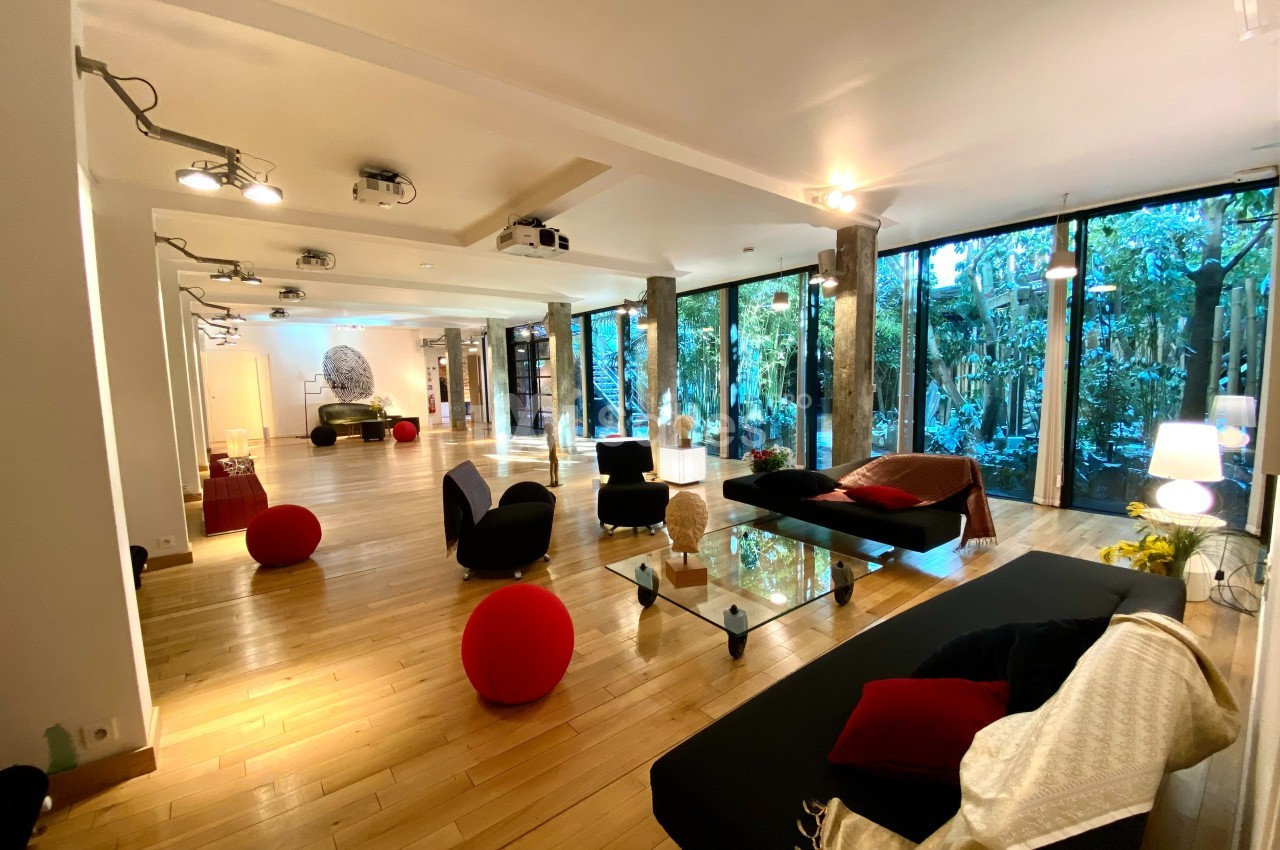 Salon spacieux et lumineux avec parquet en bois, mobilier moderne et grandes baies vitrées donnant sur un jardin.