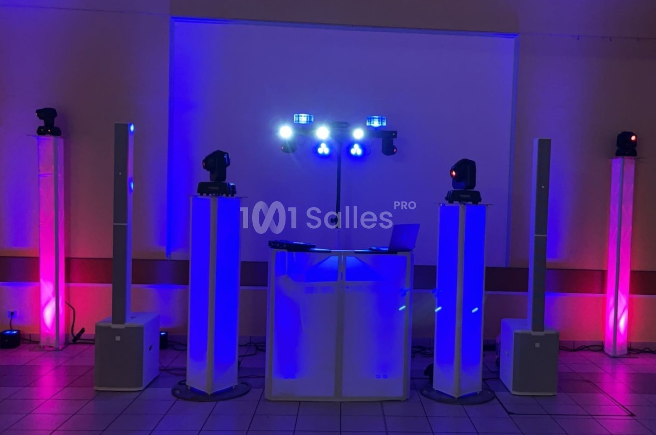 Équipement de sonorisation et éclairage avec lumières colorées installé dans une salle pour un événement.
