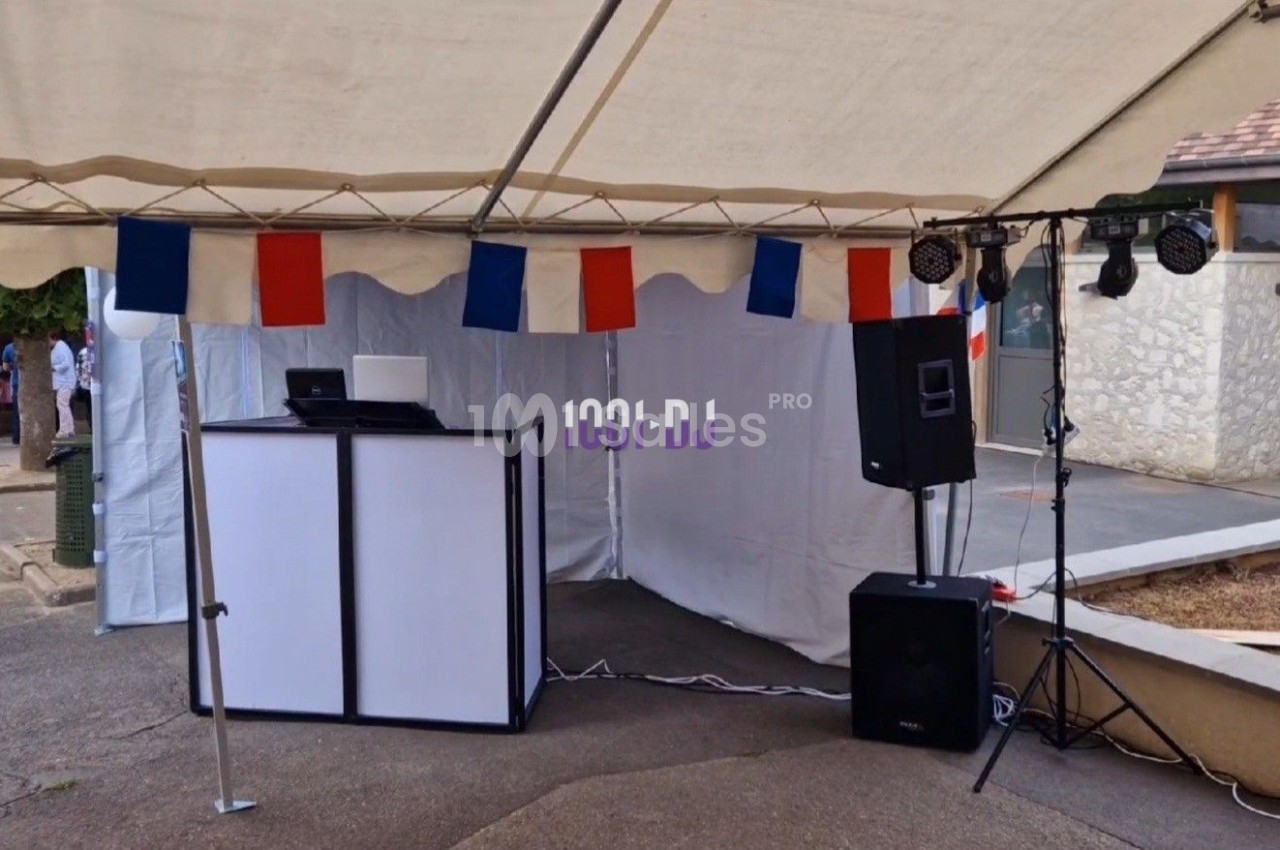 Stand de DJ sous une tente avec équipement audio et éclairage, décoré de drapeaux français.