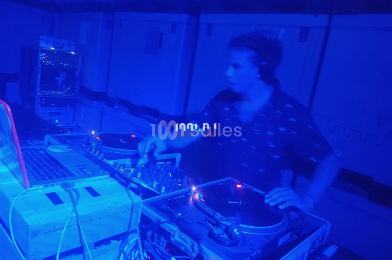 Un DJ mixant de la musique sur des platines dans une ambiance lumineuse bleue.