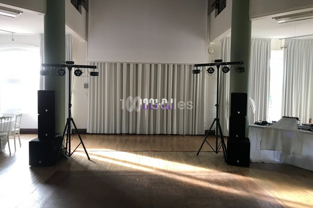 Installation de matériel audio et éclairage dans une salle lumineuse avec rideaux blancs et parquet en bois.