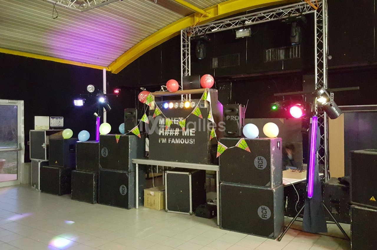Installation de matériel audio et éclairage coloré dans une salle pour un événement festif.