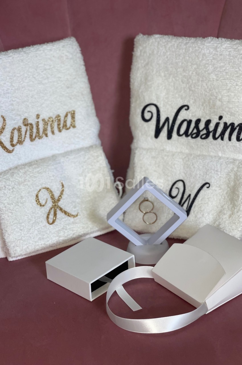 Serviettes blanches personnalisées avec des prénoms et initiales, accompagnées d'une boîte et d'un présentoir à bijoux.