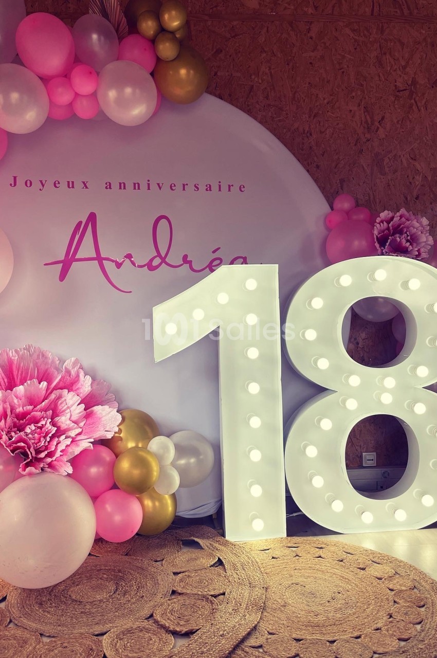 Décoration d'anniversaire avec ballons roses et dorés, panneau ’Joyeux anniversaire Andréa’ et chiffre lumineux ’18’.