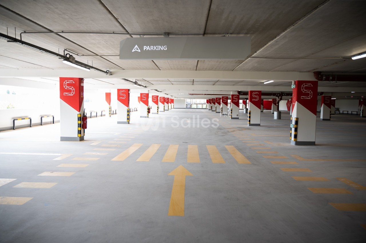 Parking intérieur vide avec marquages au sol jaunes et panneaux rouges indiquant les emplacements.