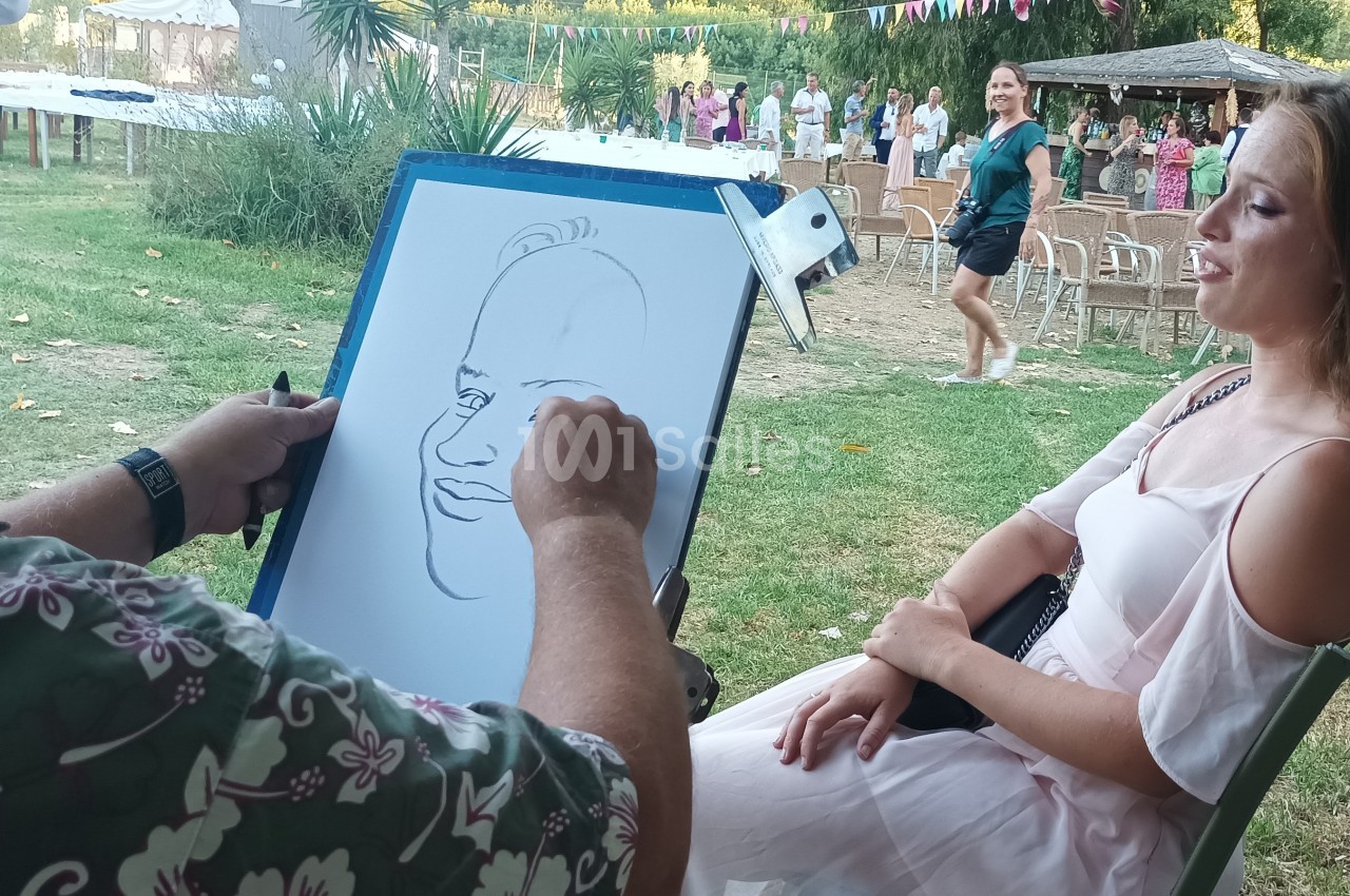 Un artiste dessine le portrait d'une femme assise en extérieur lors d'un événement en plein air.