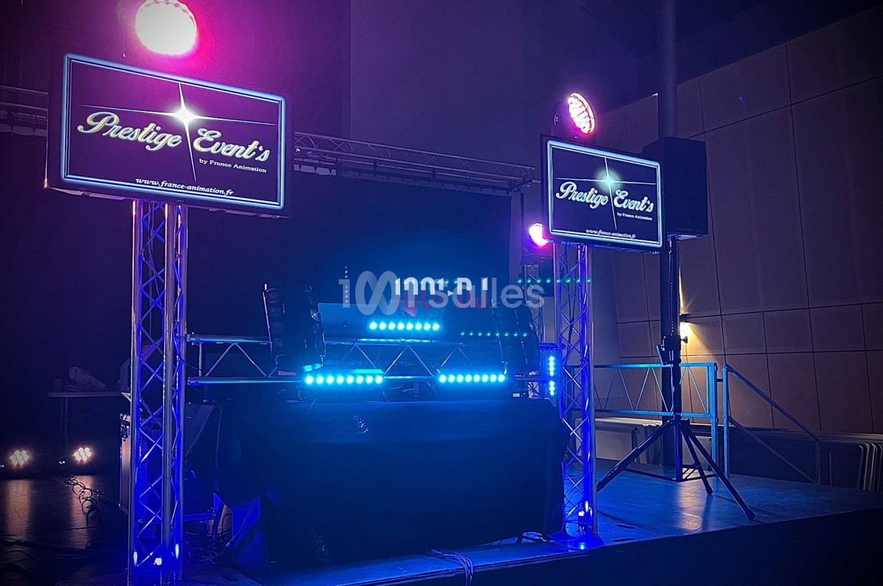 Installation de matériel de sonorisation et éclairage avec écrans affichant ’Prestige Event's’ dans une salle sombre.
