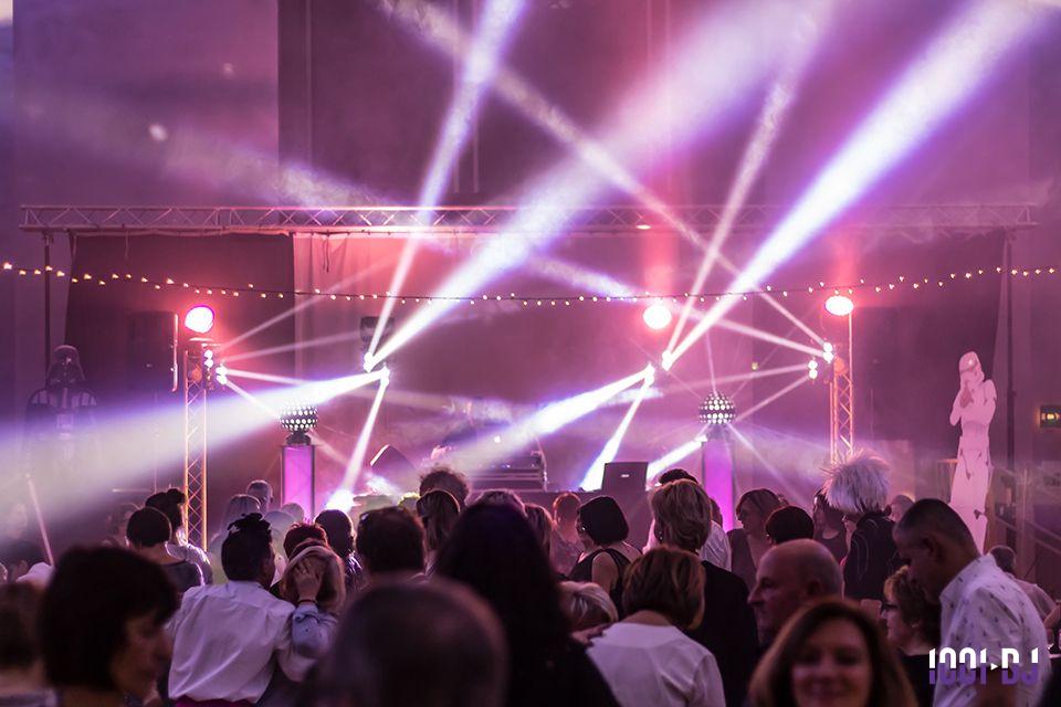 Foule dansant sous des jeux de lumière colorés lors d'une soirée festive en intérieur.