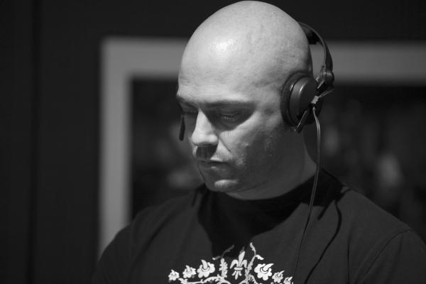 Homme chauve portant un casque audio, concentré, en noir et blanc.