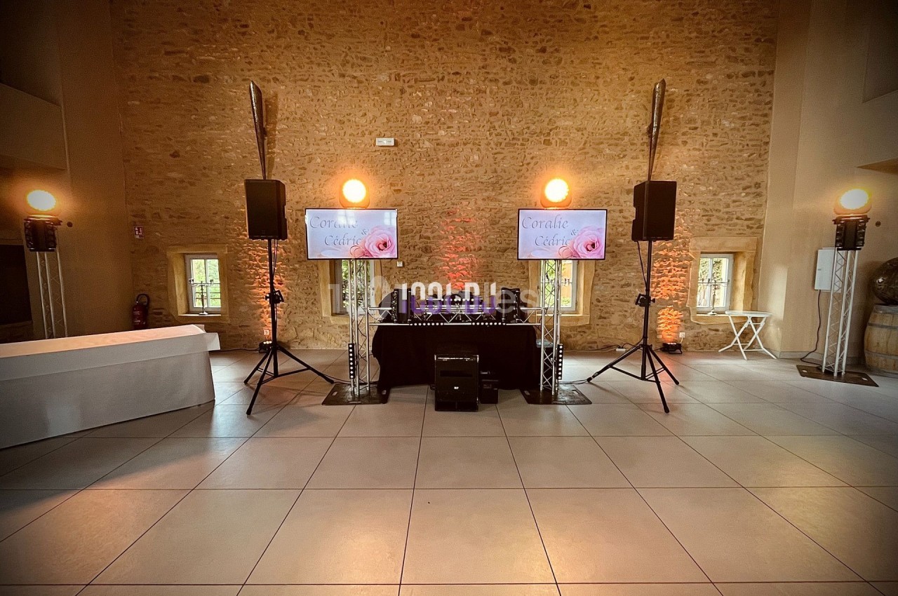 Installation de matériel de sonorisation et éclairage dans une salle en pierre avec deux écrans affichant un visuel.