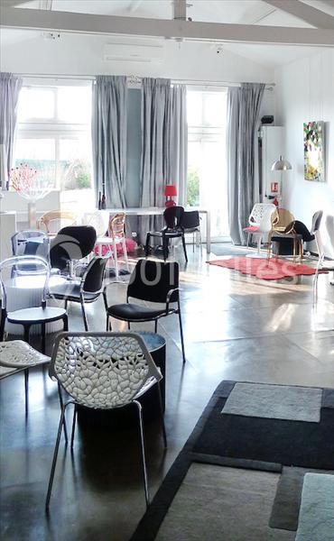 Salle lumineuse avec des chaises modernes, des tables et de grandes fenêtres laissant entrer la lumière naturelle.