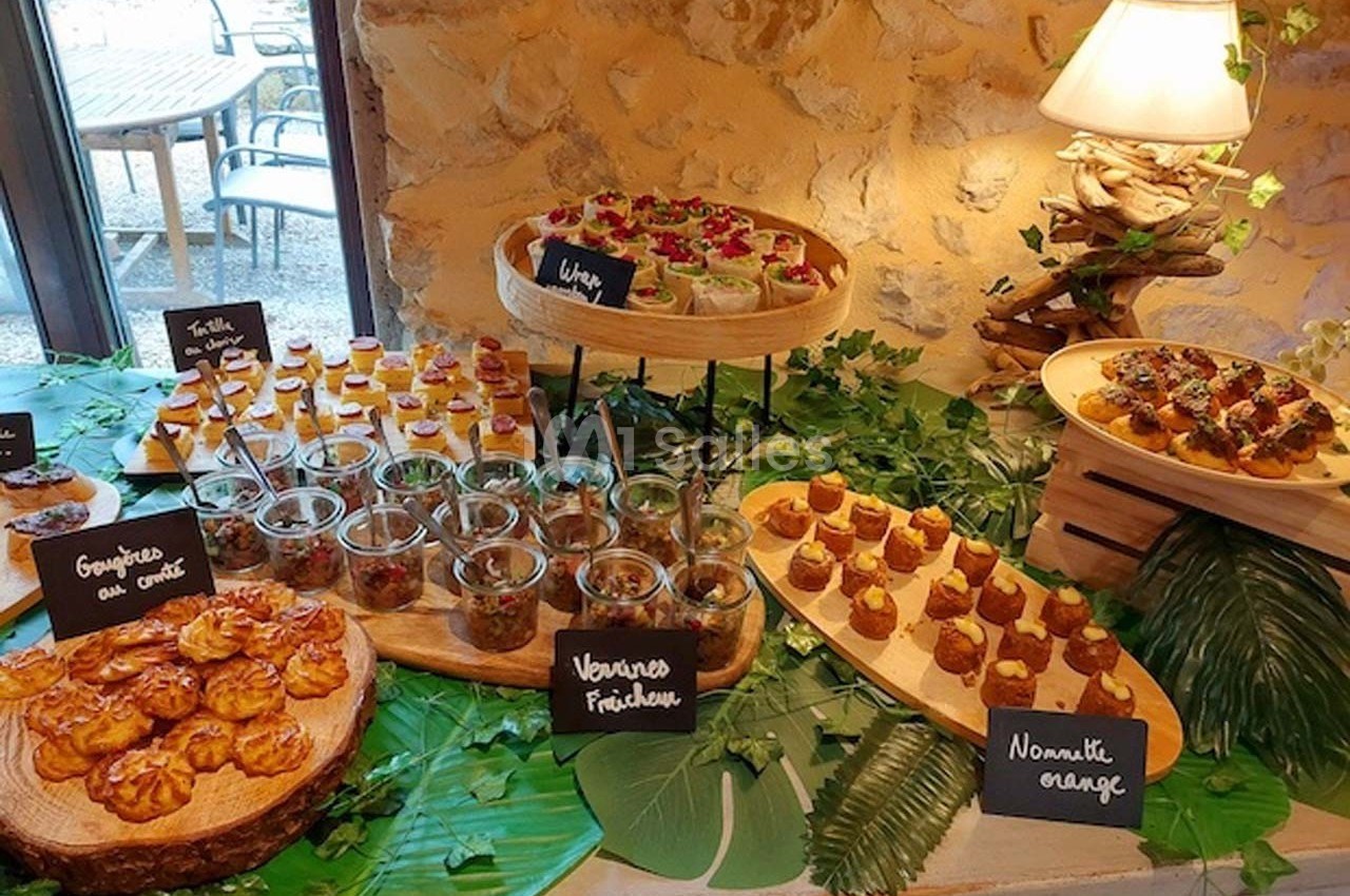 Buffet de verrines, bouchées salées et sucrées disposées sur des plateaux en bois, décoré de feuilles vertes.