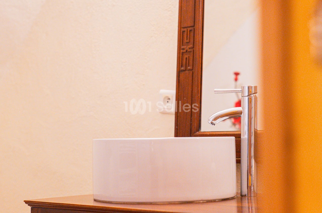 Lavabo blanc posé sur un meuble en bois avec un miroir encadré en bois en arrière-plan.