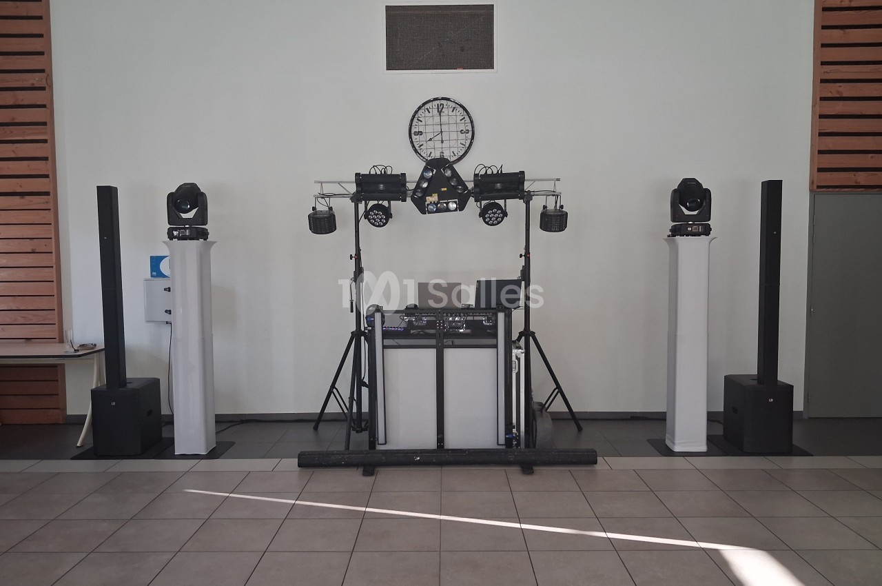 Installation de matériel de sonorisation et d'éclairage avec une table de mixage dans une salle aux murs clairs.