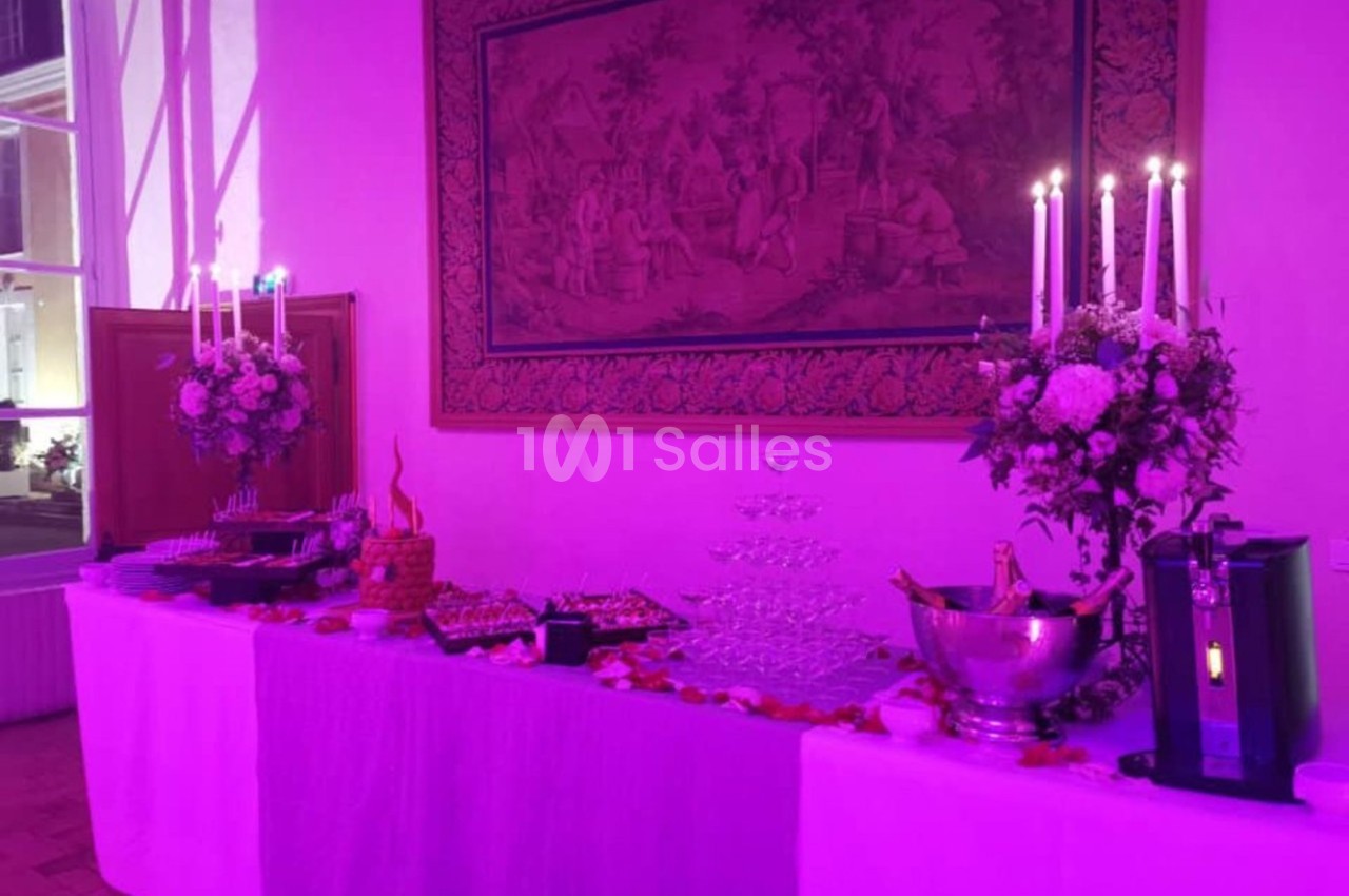Table de buffet décorée avec des fleurs, chandeliers allumés, coupes empilées et divers plats dans une ambiance lumineuse…