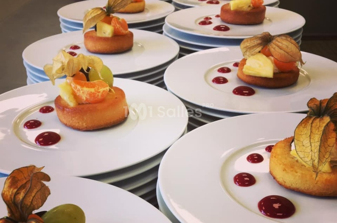 Assiettes de desserts individuels composés de gâteaux, fruits frais et décorations, disposées sur une table.