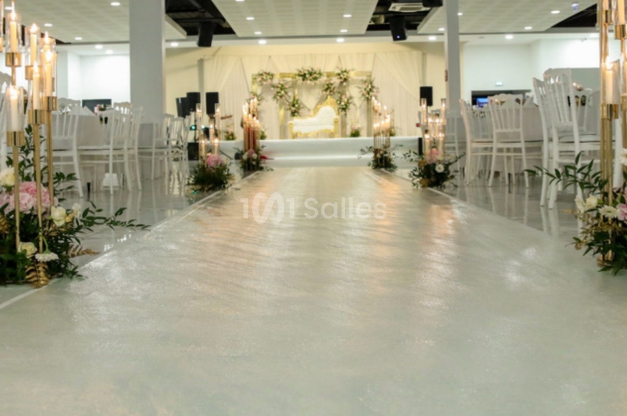 Allée centrale décorée de fleurs et bougies menant à une scène ornée pour un événement ou une cérémonie.