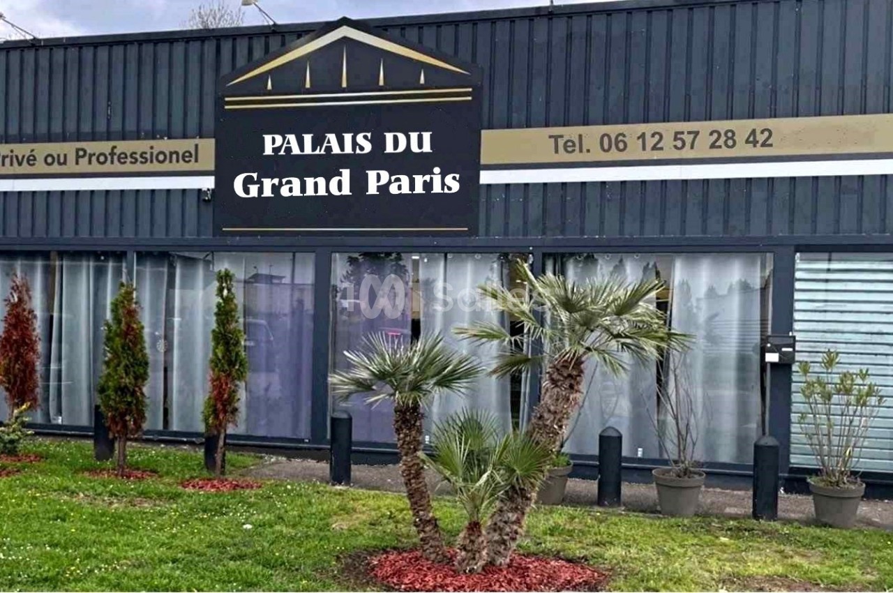 Façade d'un bâtiment avec enseigne ’Palais du Grand Paris’, entourée de plantes et d'une pelouse entretenue.