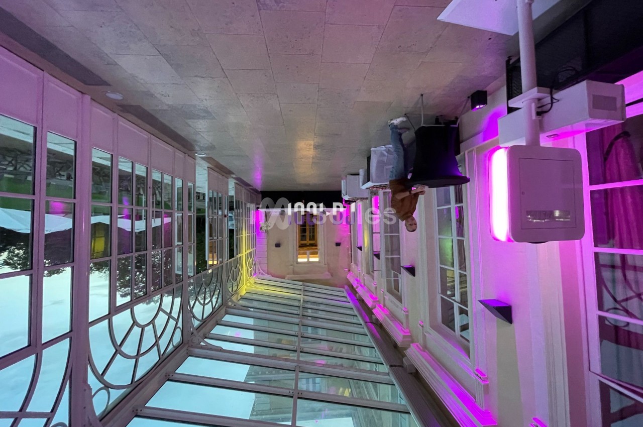 Verrière lumineuse avec éclairage violet, mobilier moderne et vue sur l'extérieur en arrière-plan.