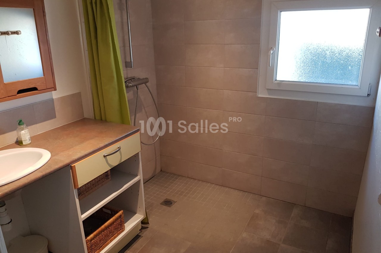 Salle de bain avec douche à l'italienne, fenêtre opaque, meuble sous lavabo et rideau de douche vert.