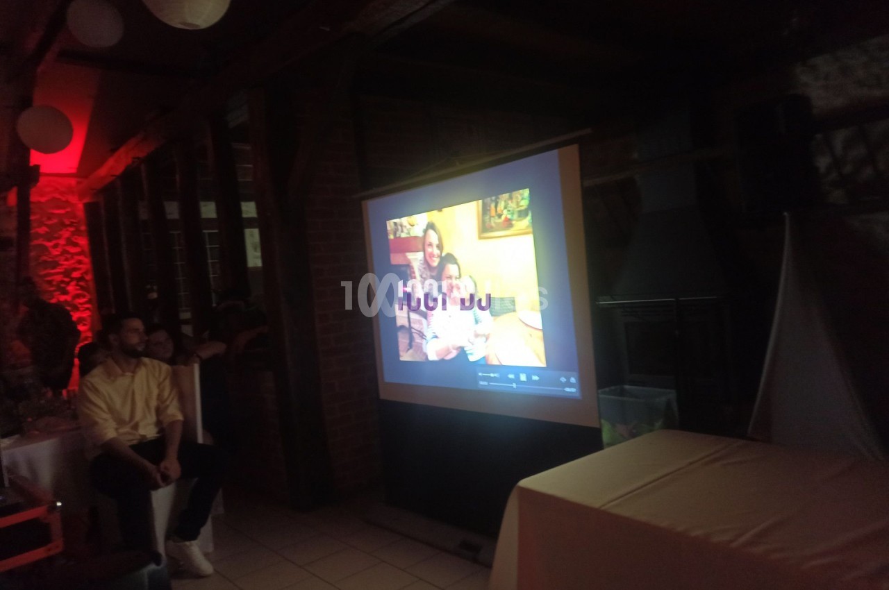 Projection d'une photo de famille sur un écran dans une salle éclairée par des lumières tamisées rouges.