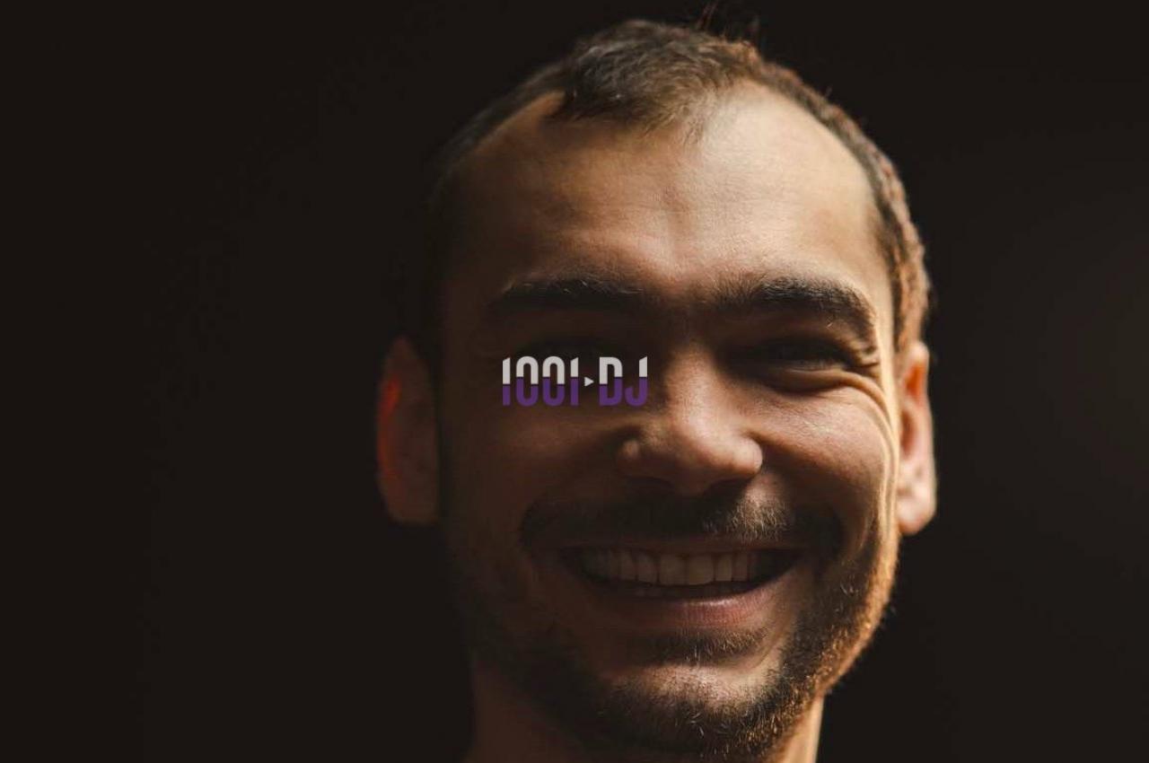 Portrait d'un homme souriant avec un éclairage tamisé sur fond sombre, un logo ’1001 DJ’ superposé au centre.