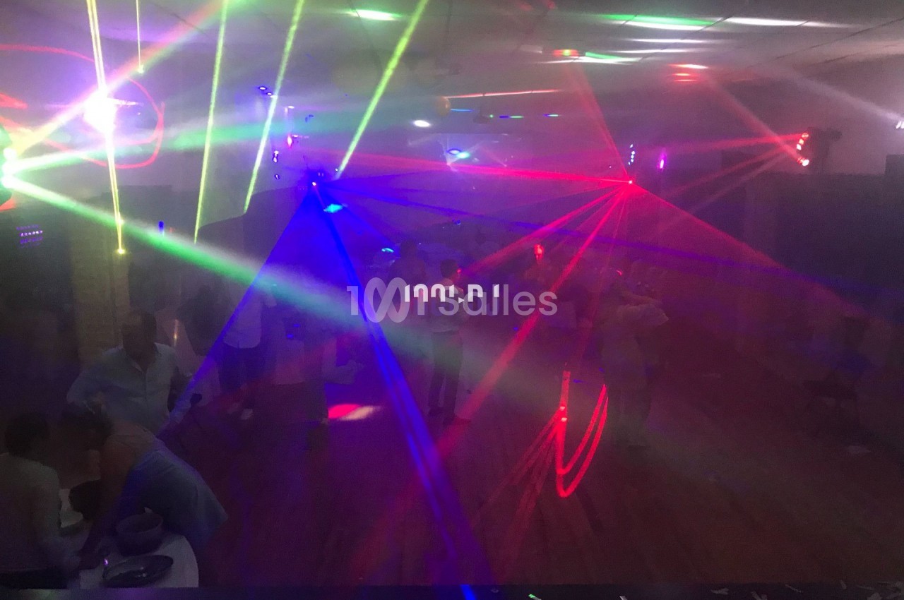 Salle sombre avec des jeux de lumières colorées et des personnes dansant sur une piste.