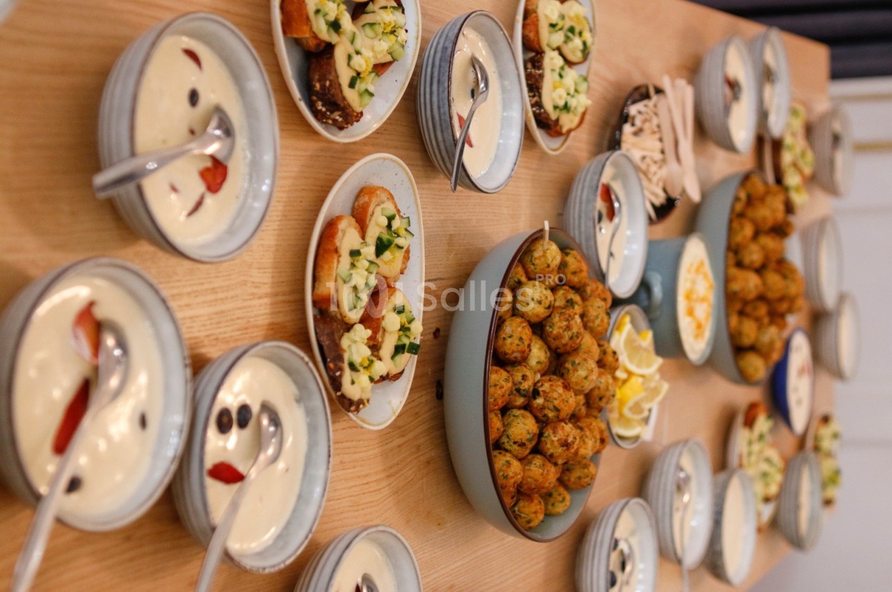 Table garnie de plats variés : boulettes, tartines garnies, sauces et accompagnements dans des assiettes et bols.