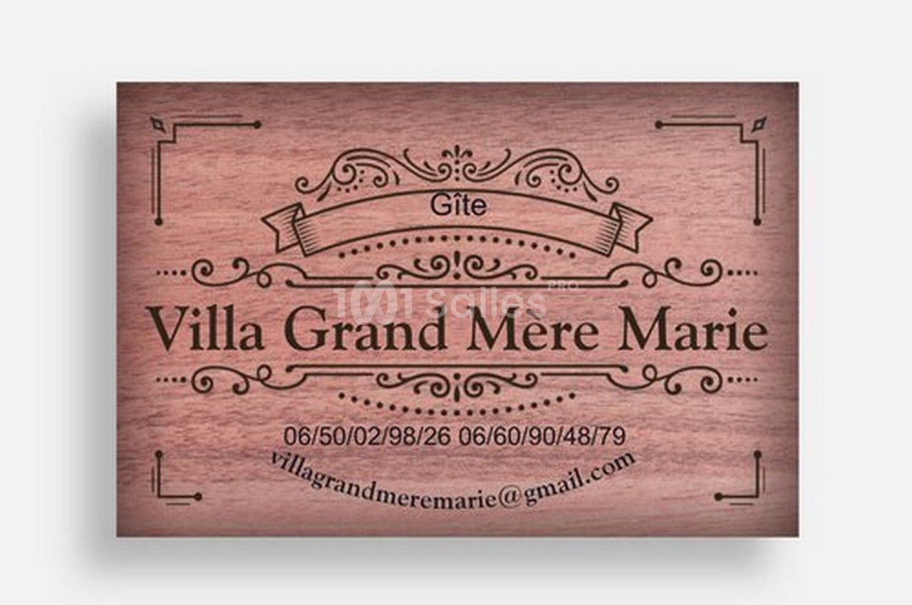 Plaque en bois gravée indiquant ’Gîte Villa Grand Mère Marie’ avec coordonnées téléphoniques et email.