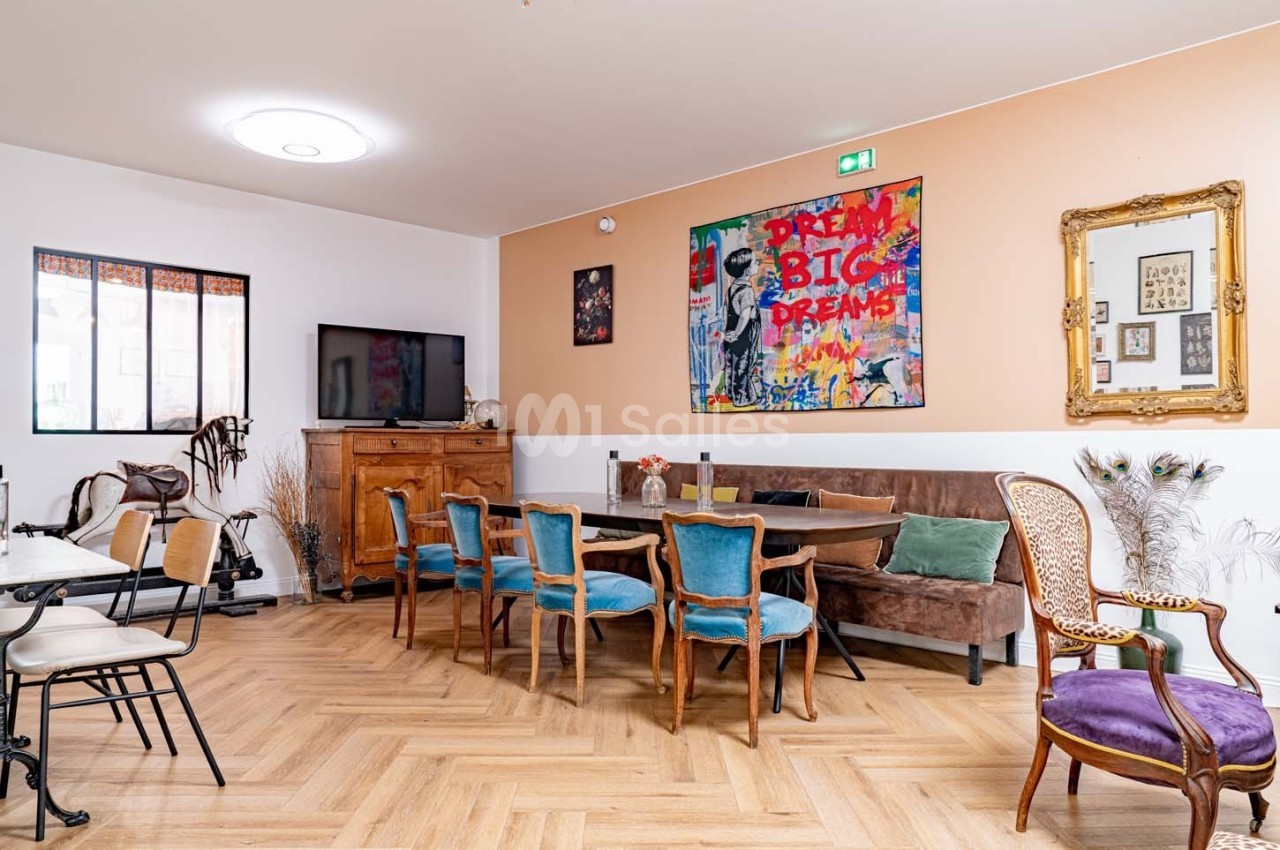 Salle à manger lumineuse avec table en bois, chaises colorées, parquet clair et décorations murales variées.