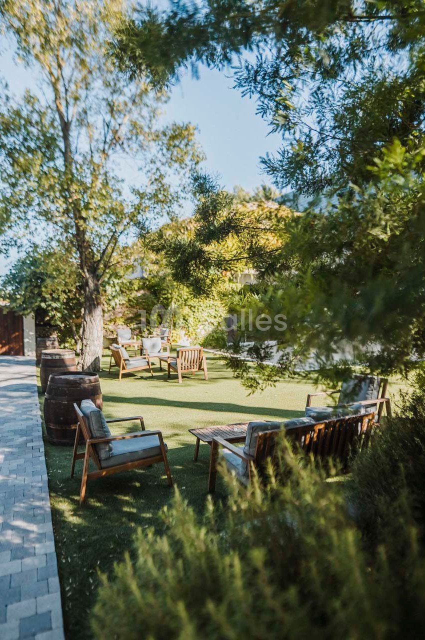 Mobilier de jardin en bois disposé sur une pelouse entourée d'arbres et de verdure, par une journée ensoleillée.
