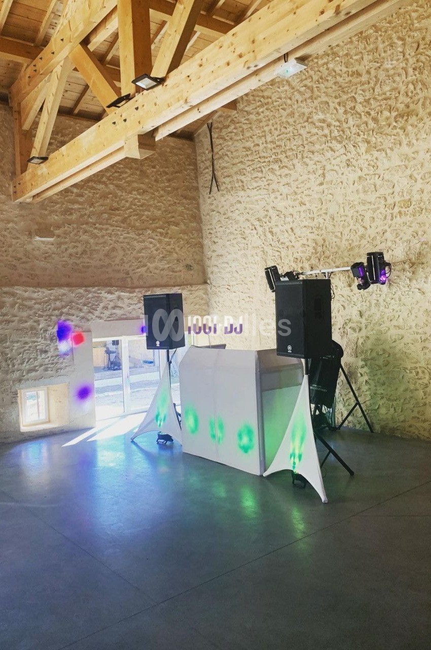 Installation de matériel de sonorisation et d'éclairage dans une salle en pierre avec charpente en bois apparente.