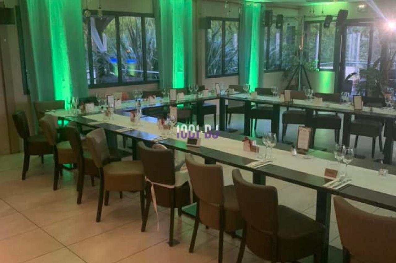 Salle de réception avec tables disposées en U, chaises alignées et éclairage vert tamisé.