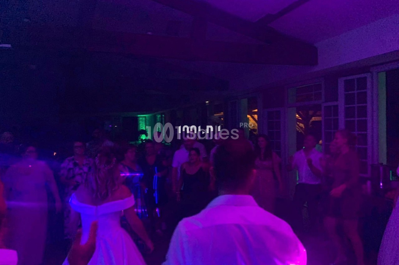 Des personnes dansent dans une salle faiblement éclairée avec des lumières colorées, lors d'une fête ou d'un événement.