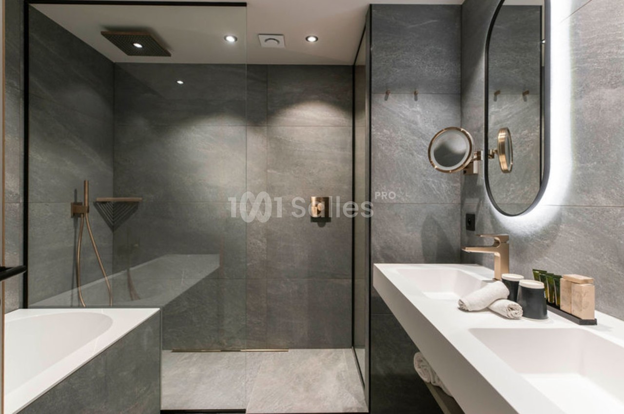 Salle de bain moderne avec douche à l'italienne, baignoire, double vasque et éclairage intégré.