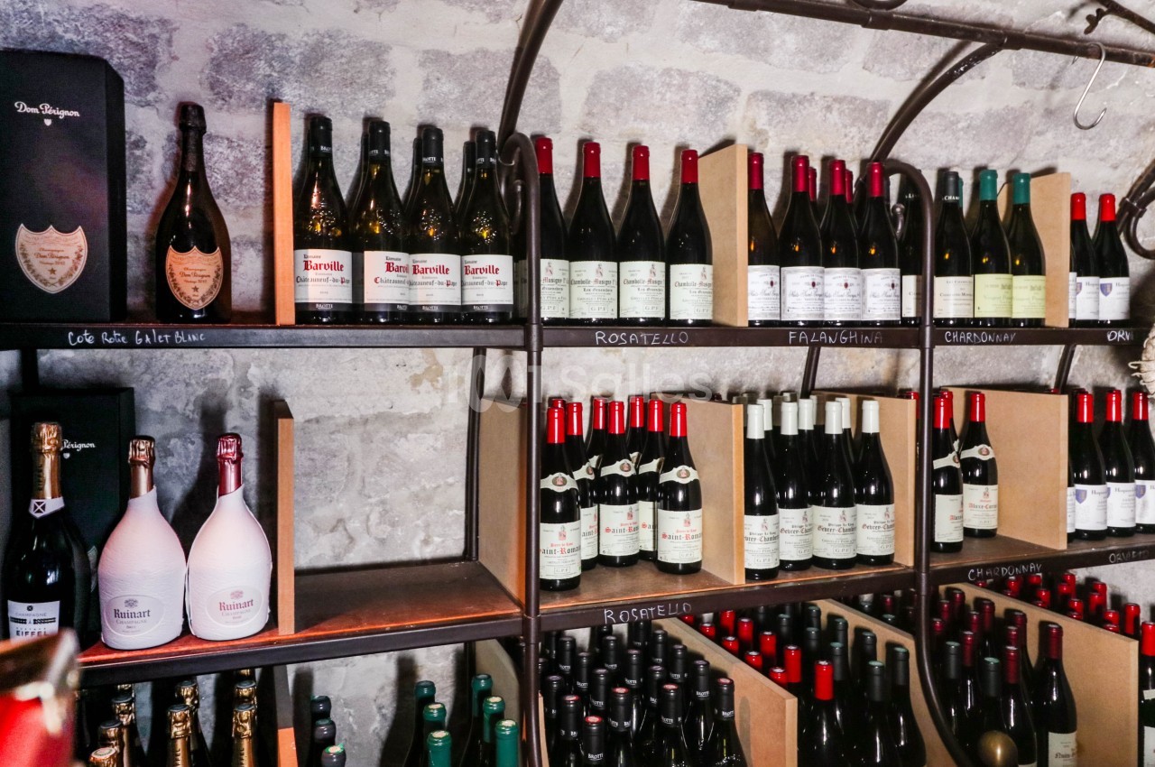 Étagères remplies de bouteilles de vin et de champagne dans une cave en pierre.